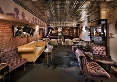 a living room filled with lots of furniture and walls covered in metal pipes that are hanging from the ceiling