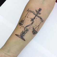 a tattoo on the arm of a person with a scale and hourglass in it