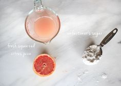 grapefruit, sugar, and other ingredients to make an orangeade cocktail on a marble counter top