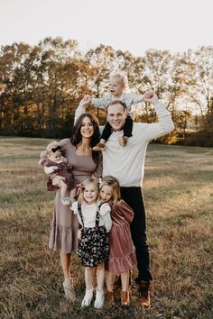 a family posing for a photo in a field with their two children and one adult