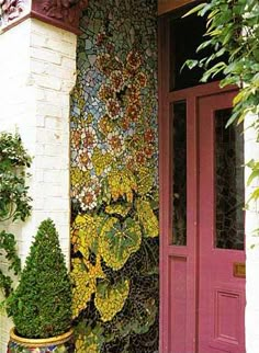 a red door and some plants on the side of a building