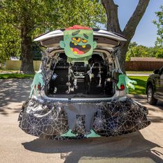 the back end of a car with decorations on it's trunk, and an image of a green monster sticking out of its trunk