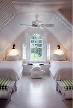 two beds in a room with white walls and ceiling fan above them is a window that looks out onto the yard