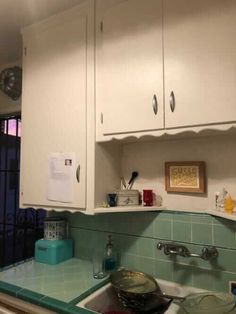 a kitchen with white cabinets and green counter tops, blue tile backsplashes