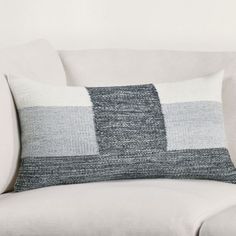 a white couch with a gray and black pillow on it's backrests