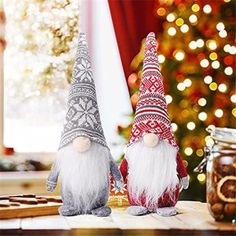 two gnome figurines sitting next to each other on a table in front of a christmas tree