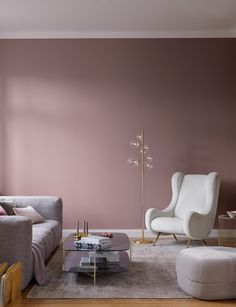 a living room with pink walls and two white chairs in front of a coffee table