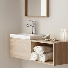 a bathroom sink with towels stacked on the shelf below it and a mirror above it