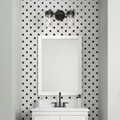 a bathroom with black and white polka dot wallpaper, two sinks and a mirror