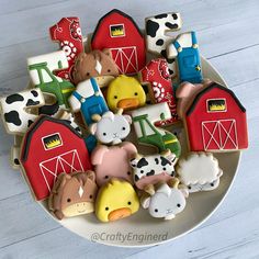 decorated cookies in the shape of farm animals and barnyards are on a plate