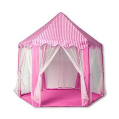 a pink and white tent with curtains on the top is sitting in front of a white wall