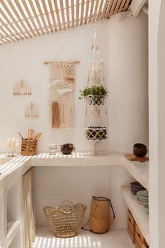 a room with white walls and shelves filled with baskets, wicker baskets and plants