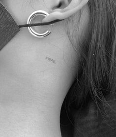 black and white photograph of a woman's neck with ear piercings on it