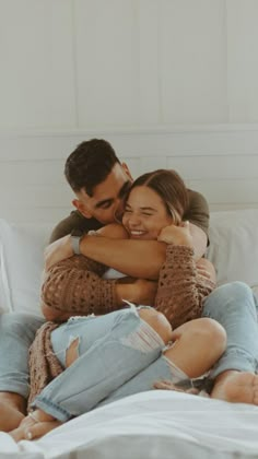 a man and woman cuddling on top of a bed in the middle of their day