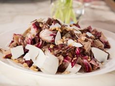 a white plate topped with lots of food on top of a table next to a vase filled with flowers