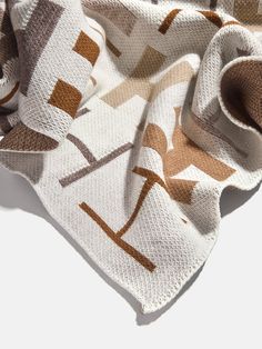 a white scarf with brown and tan geometric designs on the front, folded over it