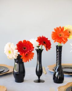 three black vases filled with colorful flowers on top of a table