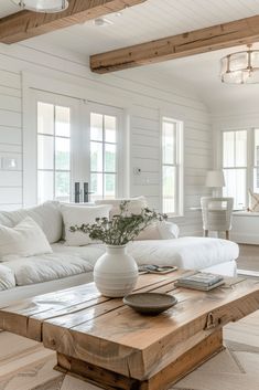 a living room with white furniture and wood beams