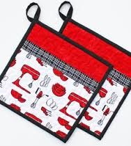 two oven mitts with red and white kitchen utensils on them, sitting side by side