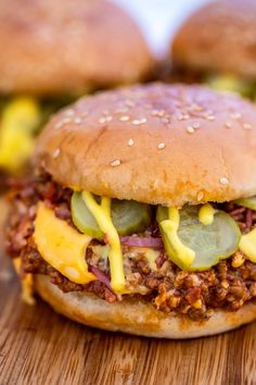 two hamburgers with cheese and pickles on a wooden board, ready to be eaten