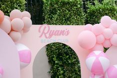 pink and white balloons decorate the entrance to a beach club