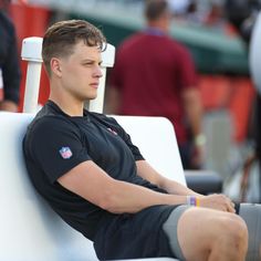 a young man sitting on top of a white bench in front of a group of people