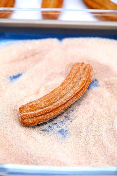 some kind of food that is on top of sand in a pan with other foods behind it