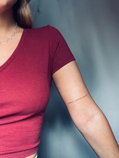 a woman with a small tattoo on her left arm, wearing a red shirt and white pants