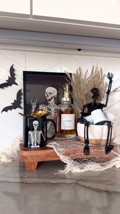 a table topped with halloween decorations and bottles on top of a wooden shelf next to a framed