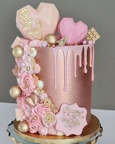 a pink and gold birthday cake with decorations