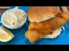 a blue plate topped with a chicken sandwich and cole slaw