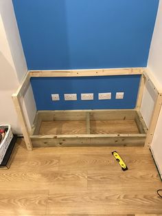 a wooden bench sitting on top of a hard wood floor next to a blue wall