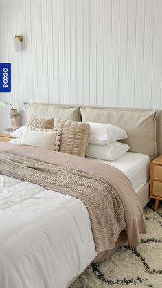 a bed with white sheets and pillows in a bedroom