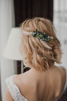 the back of a woman's head with flowers in her hair and leaves on it