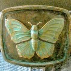 a green belt with a butterfly buckle on it's back pocket and jeans in the background