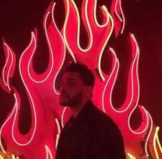 a man standing in front of a red and yellow wall with neon flames on it