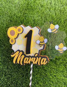 a cake topper with the number one on it and some bees in the grass