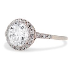 an old - fashioned diamond ring with diamonds on the band and center stone, set in 18k white gold