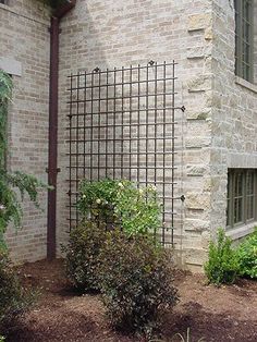 a brick building with a metal fence next to it and flowers in the foreground