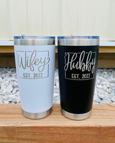 two black and white tumblers sitting on top of a wooden table next to each other