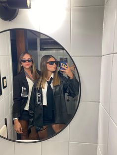 two women taking a selfie in the bathroom mirror