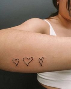 a woman's arm with three hearts tattooed on the left side of her arm