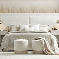 a bed with white sheets and pillows in a bedroom next to two lamps on either side of the bed