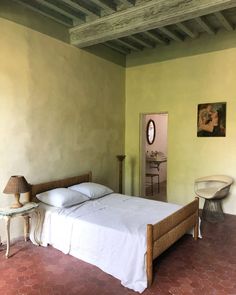 a bed in a room with yellow walls and red tile flooring on the ground