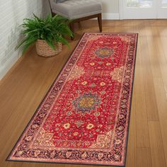 a large red rug is on the floor next to a chair and potted plant