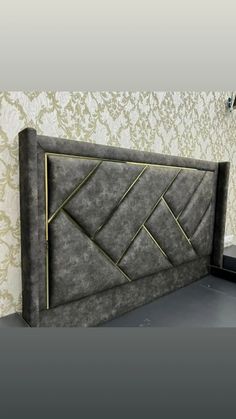 a bed that is made out of some kind of fabric with gold lines on the headboard