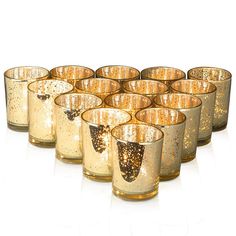 a set of twelve gold colored glasses with designs on the inside and outside, all lined up in rows