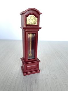 a small red clock sitting on top of a wooden table