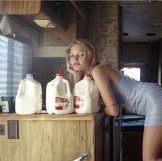 a woman leaning on a counter next to milk bottles