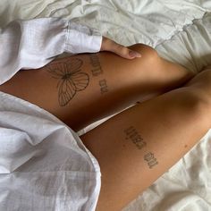 a woman laying on top of a bed with tattoos on her legs and arms behind her back